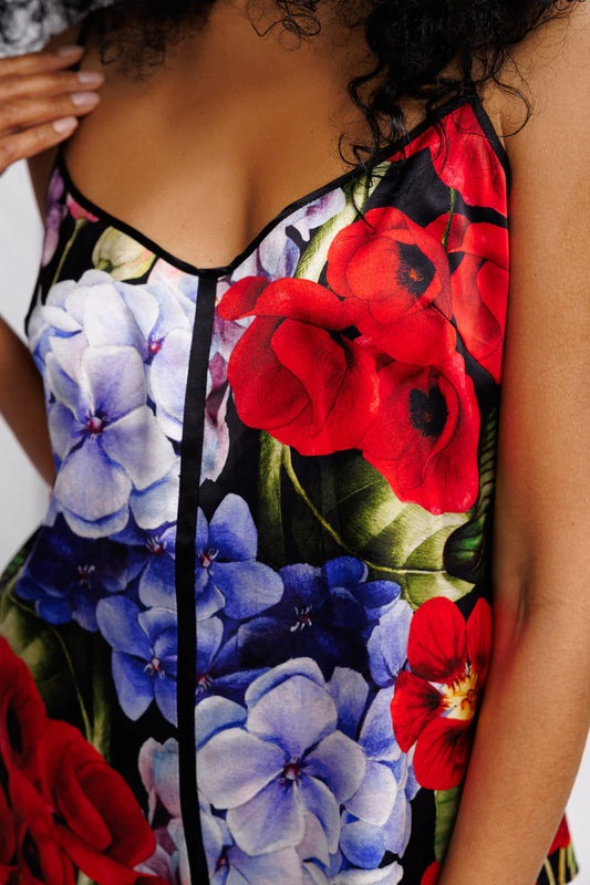 Close-up of a floral silk set of top and shorts with red and blue flowers on a black background.
