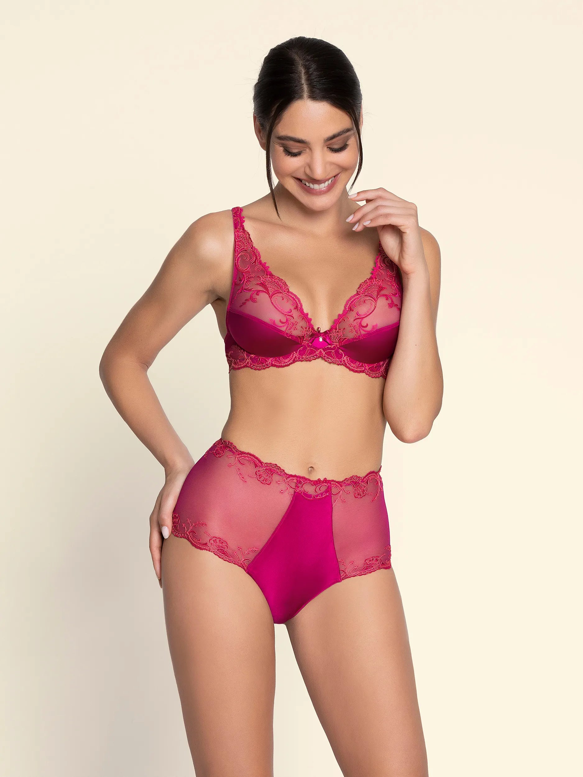 Woman wearing a pink lingerie set on a beige background